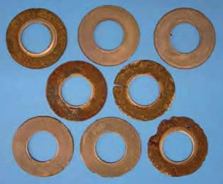 Set of disc springs after 4 weeks of immersion: varying degrees of visible attack — from surface patina to deep corrosion of the coating.